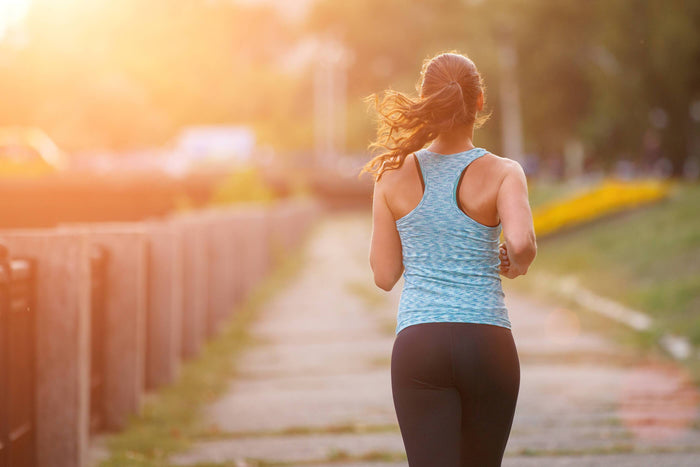 women runs down a sidewalk at sunset