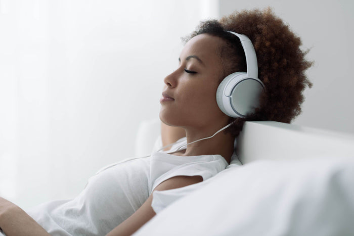 women lays in bed while listening to music