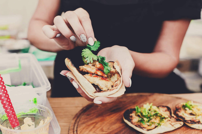 women adds cilantro to fresh tacos