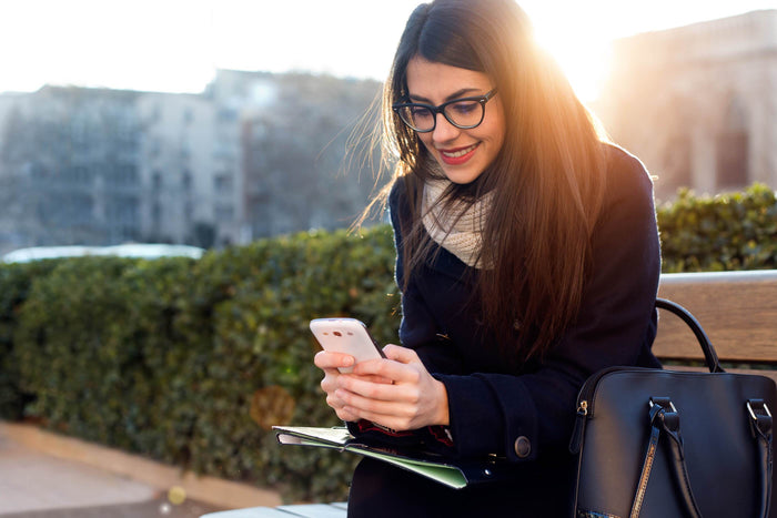 women smiles while looking at her phone